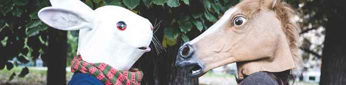 2 Menschen mit Tiermasken -Hase und Pferd- stehen sich gegenüber