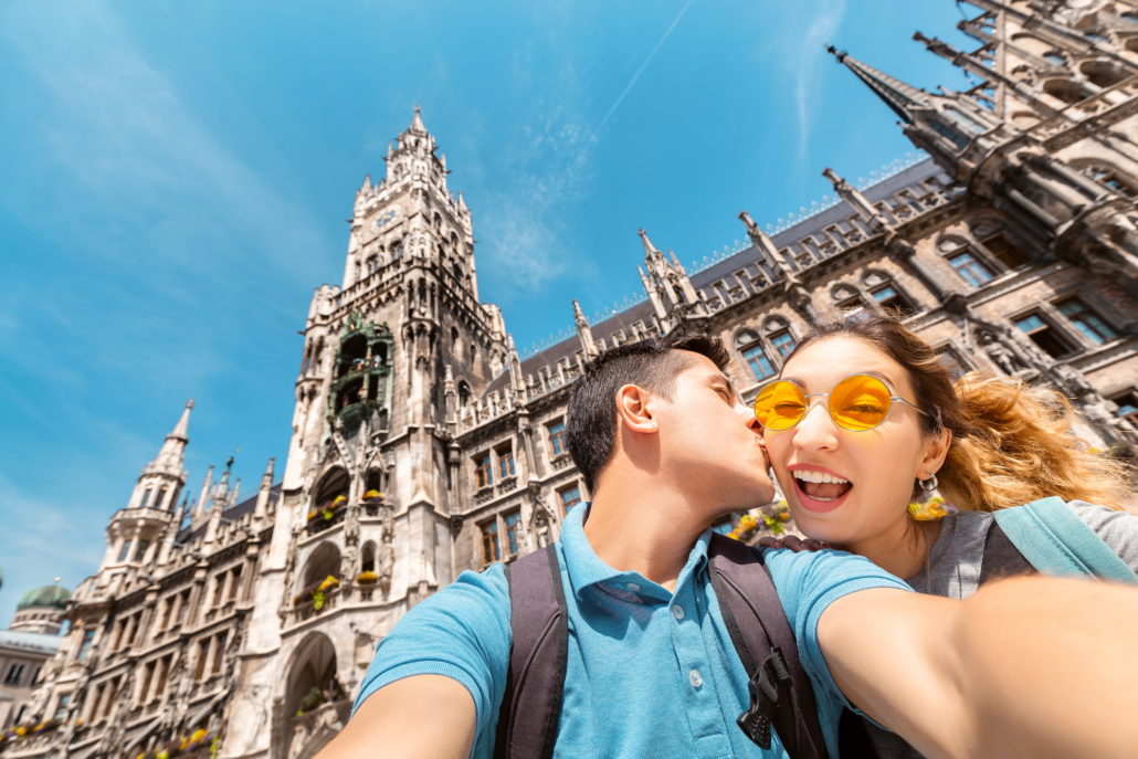 Date-Ideen in München: Ein junges Paar macht ein Selfie vor dem Rathausturm in München.