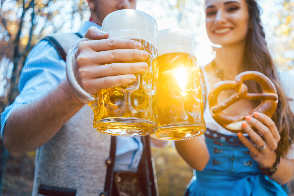 Date-Ideen in München: Junges Paar stößt im Freien stehend mit Biergläsern an